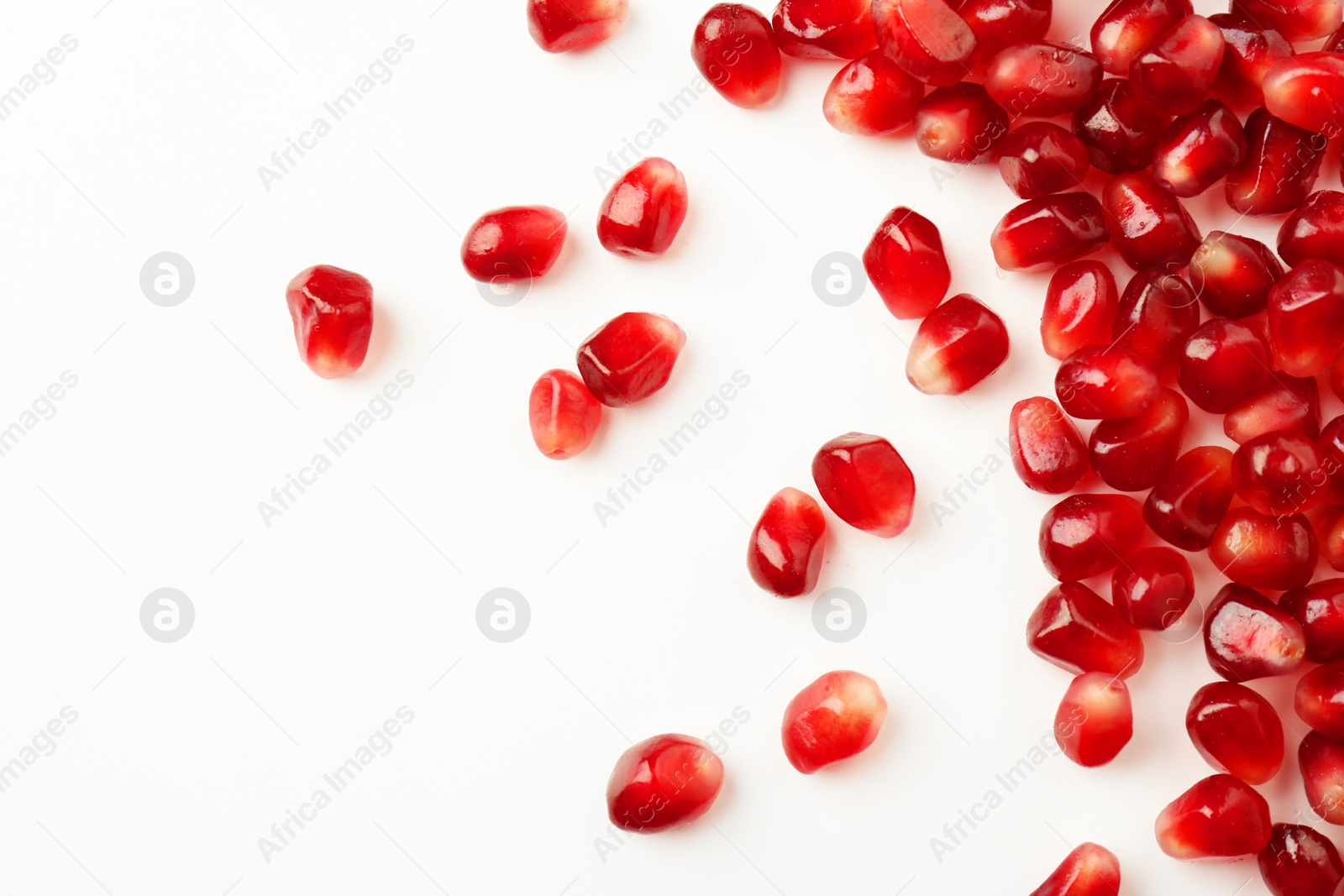 Photo of Many ripe juicy pomegranate grains on white background, flat lay. Space for text