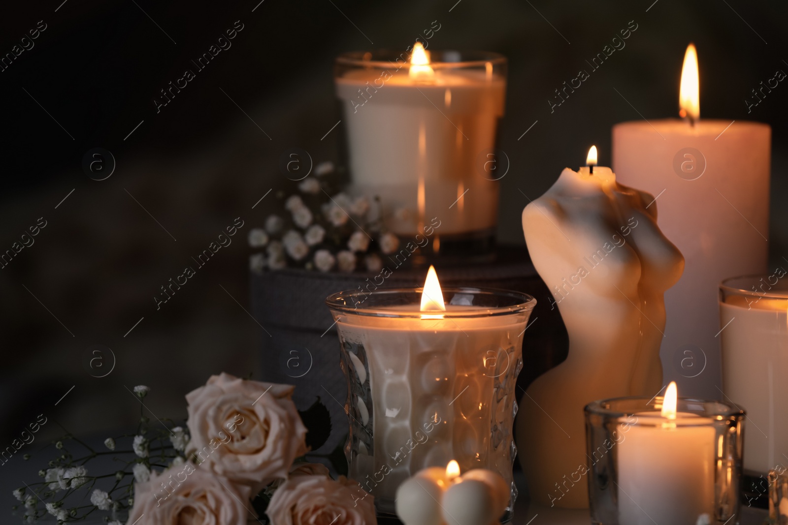 Photo of Beautiful burning candles and flowers on blurred background