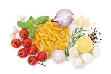 Photo of Uncooked fusilli pasta and ingredients on white background, top view