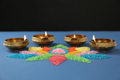 Diwali celebration. Diya lamps and colorful rangoli on blue background
