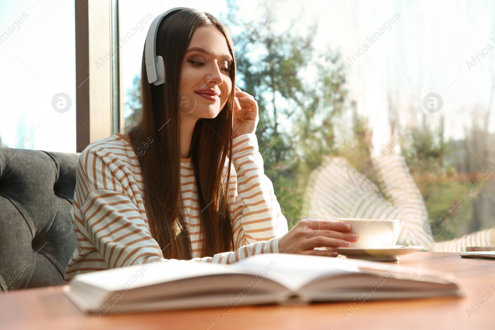 Photo of Woman listening to audiobook at table in cafe