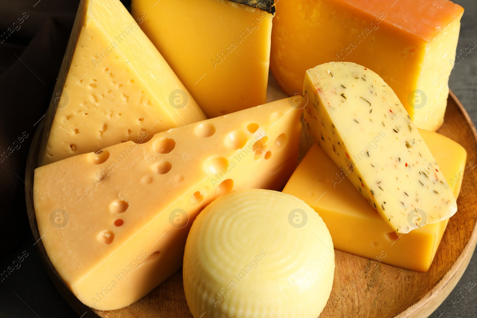 Photo of Different kinds of tasty cheese on wooden plate, closeup