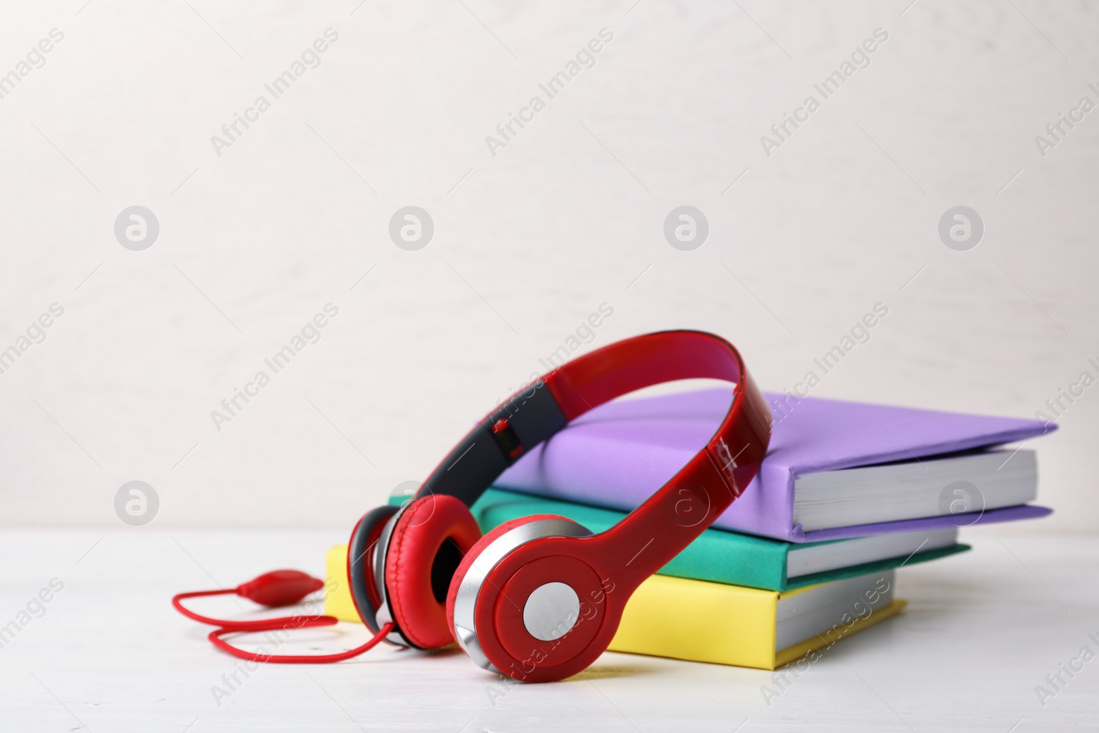 Photo of Modern headphones with hardcover books on table. Space for text