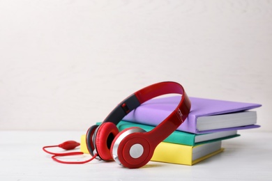 Modern headphones with hardcover books on table. Space for text