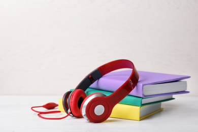 Photo of Modern headphones with hardcover books on table. Space for text