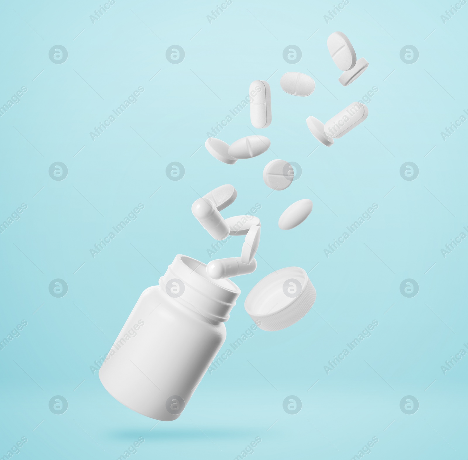 Image of Many different white pills falling into bottle on light blue background