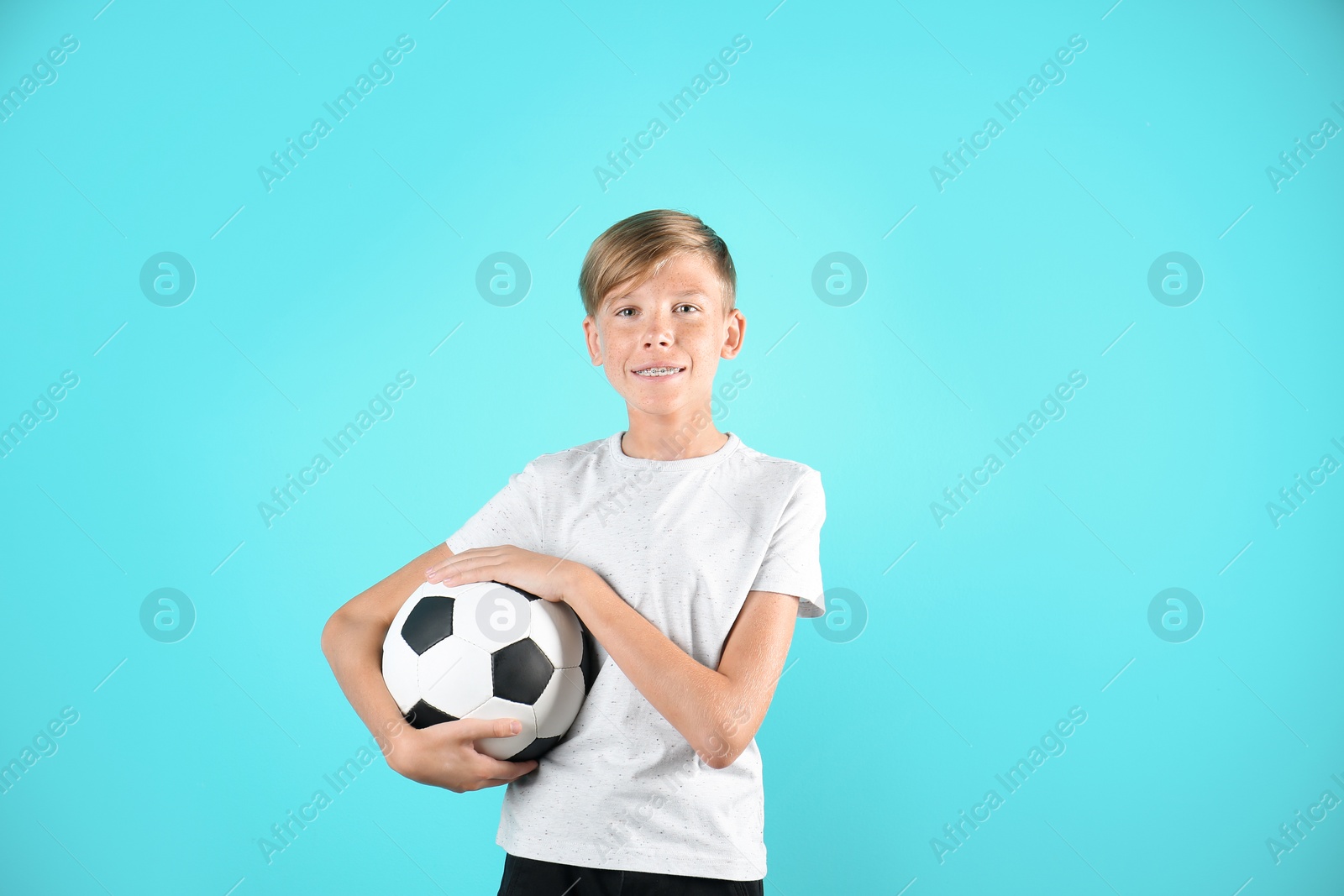 Photo of Portrait of young boy holding soccer ball on color background