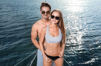 Photo of Young man and his beautiful girlfriend in bikini on yacht. Happy couple on vacation