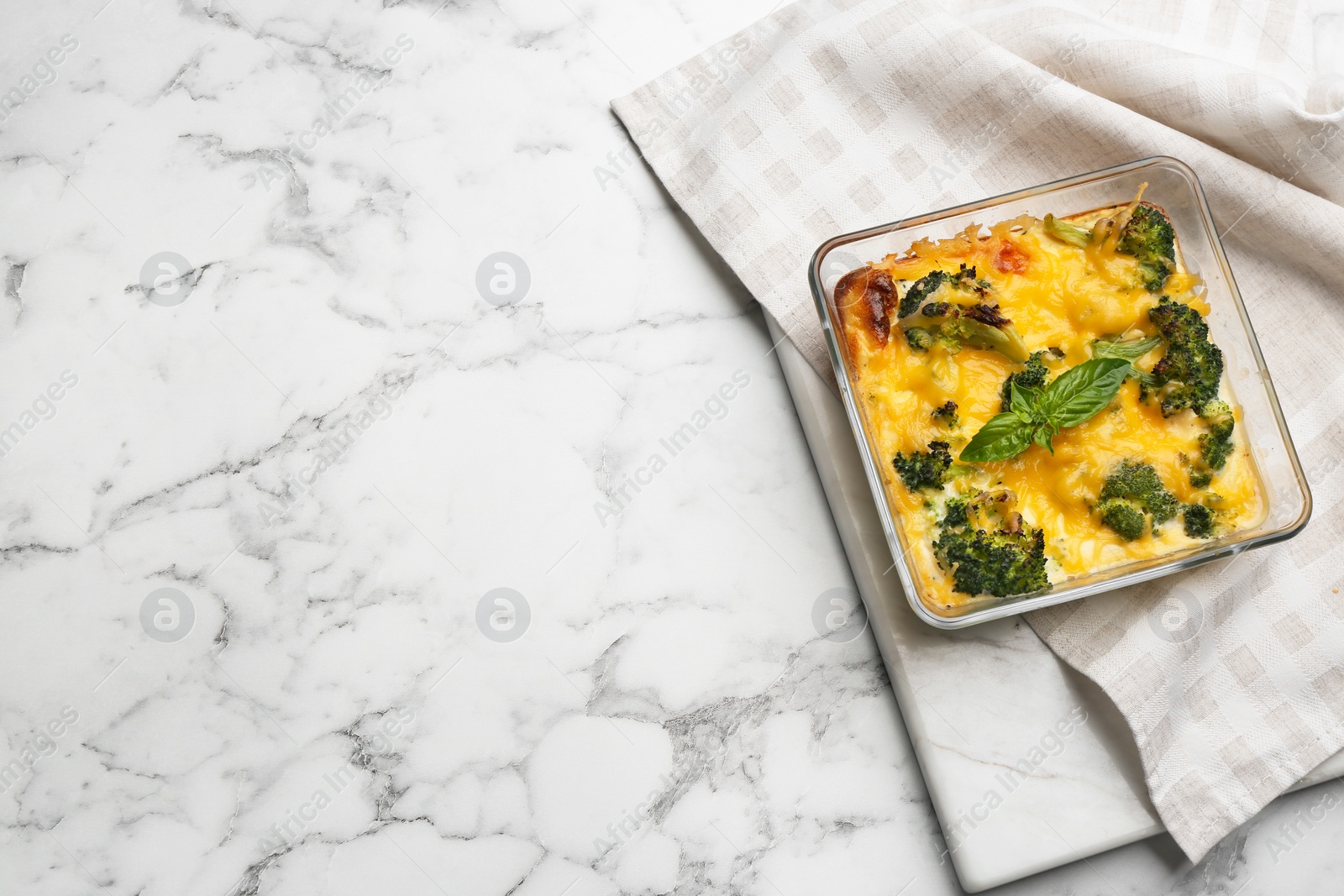 Photo of Tasty broccoli casserole in baking dish on white marble table, top view. Space for text