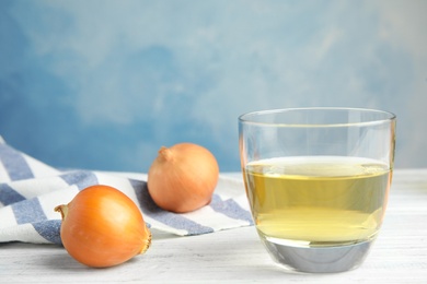 Photo of Glass of onion syrup and fresh vegetable on table. Space for text