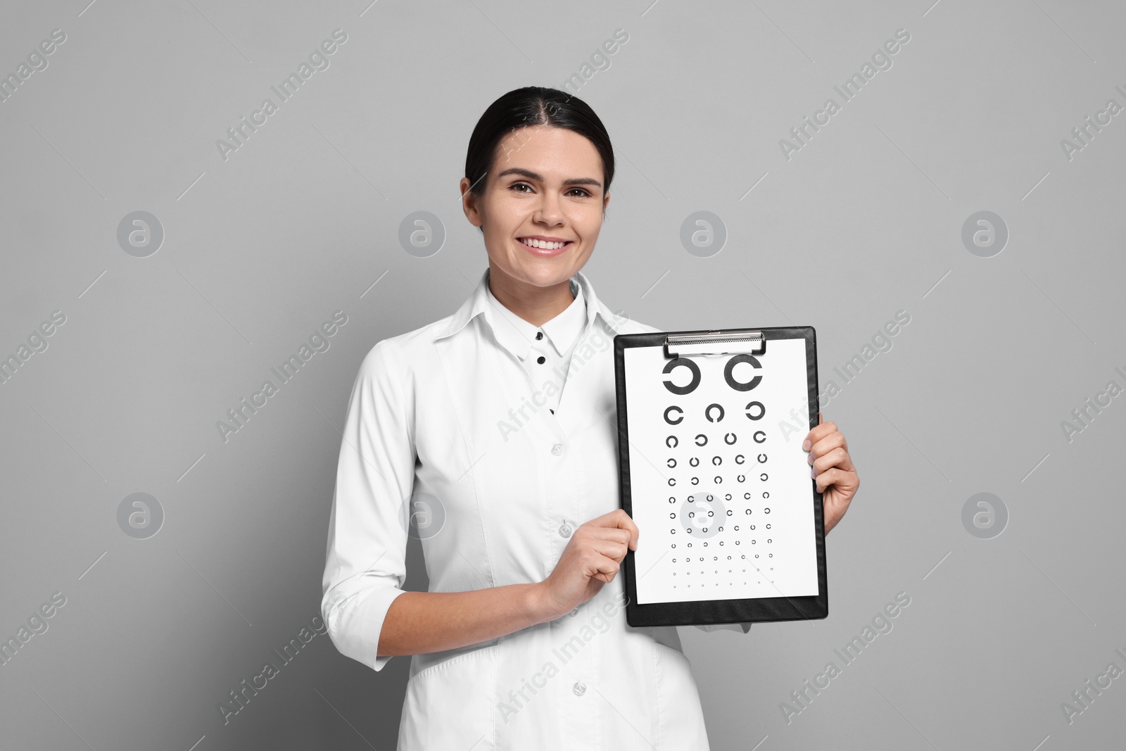 Photo of Ophthalmologist with vision test chart on gray background