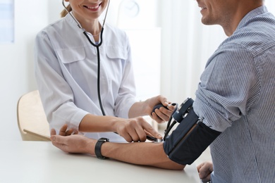 Doctor checking patient's blood pressure in hospital, closeup. Cardiology concept