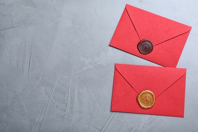 Photo of Red envelopes with wax seals on grey background, flat lay. Space for text
