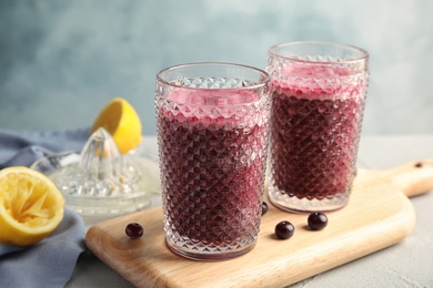 Photo of Glasses of delicious acai juice on table against color background