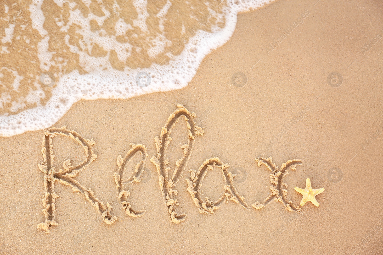 Photo of Word "RELAX" written on sandy beach and sea wave, top view