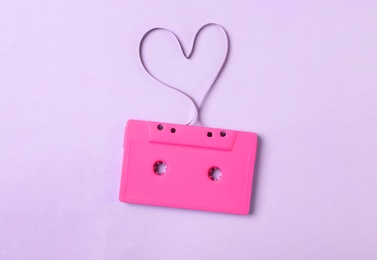 Photo of Music cassette and heart made with tape on violet background, top view. Listening love song