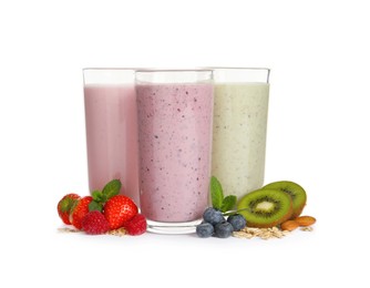 Photo of Glasses of different oatmeal smoothies and fresh ingredients on white background