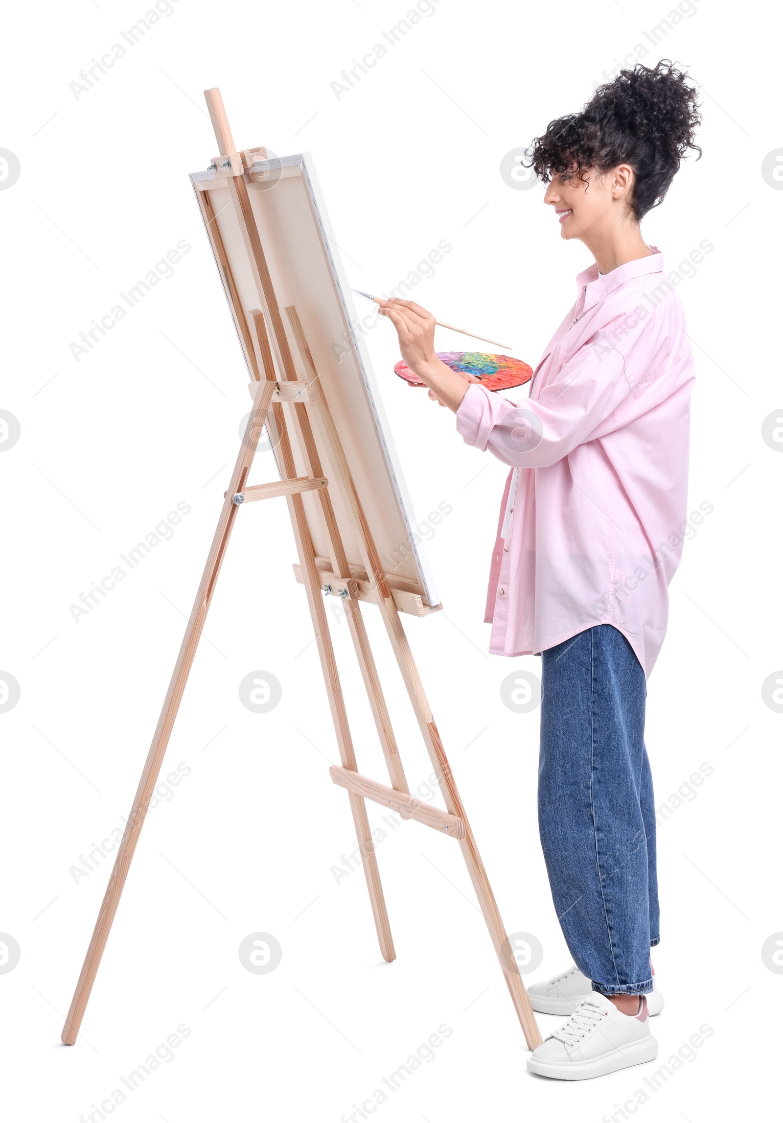 Photo of Young woman painting on easel with canvas against white background