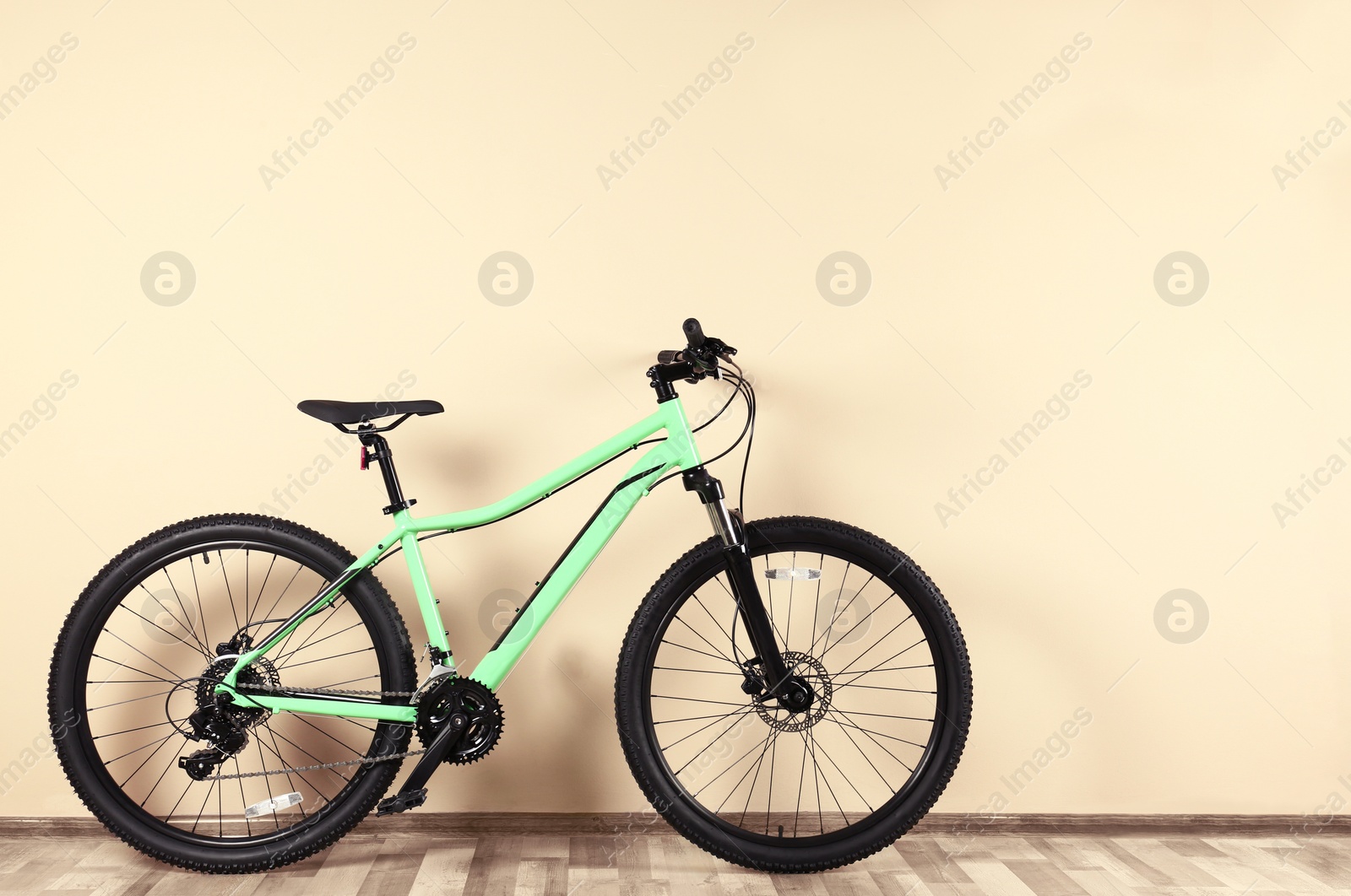 Photo of Modern bicycle near beige wall indoors. Healthy lifestyle