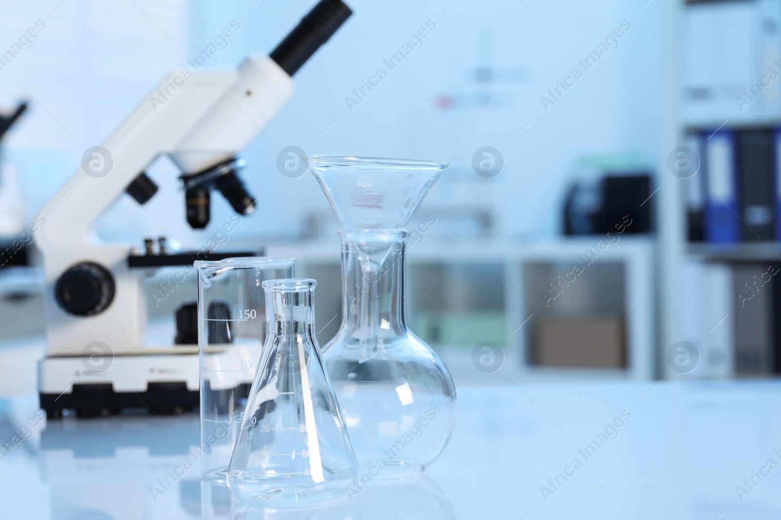 Photo of Laboratory analysis. Different glassware and microscope on white table indoors, closeup. Space for text