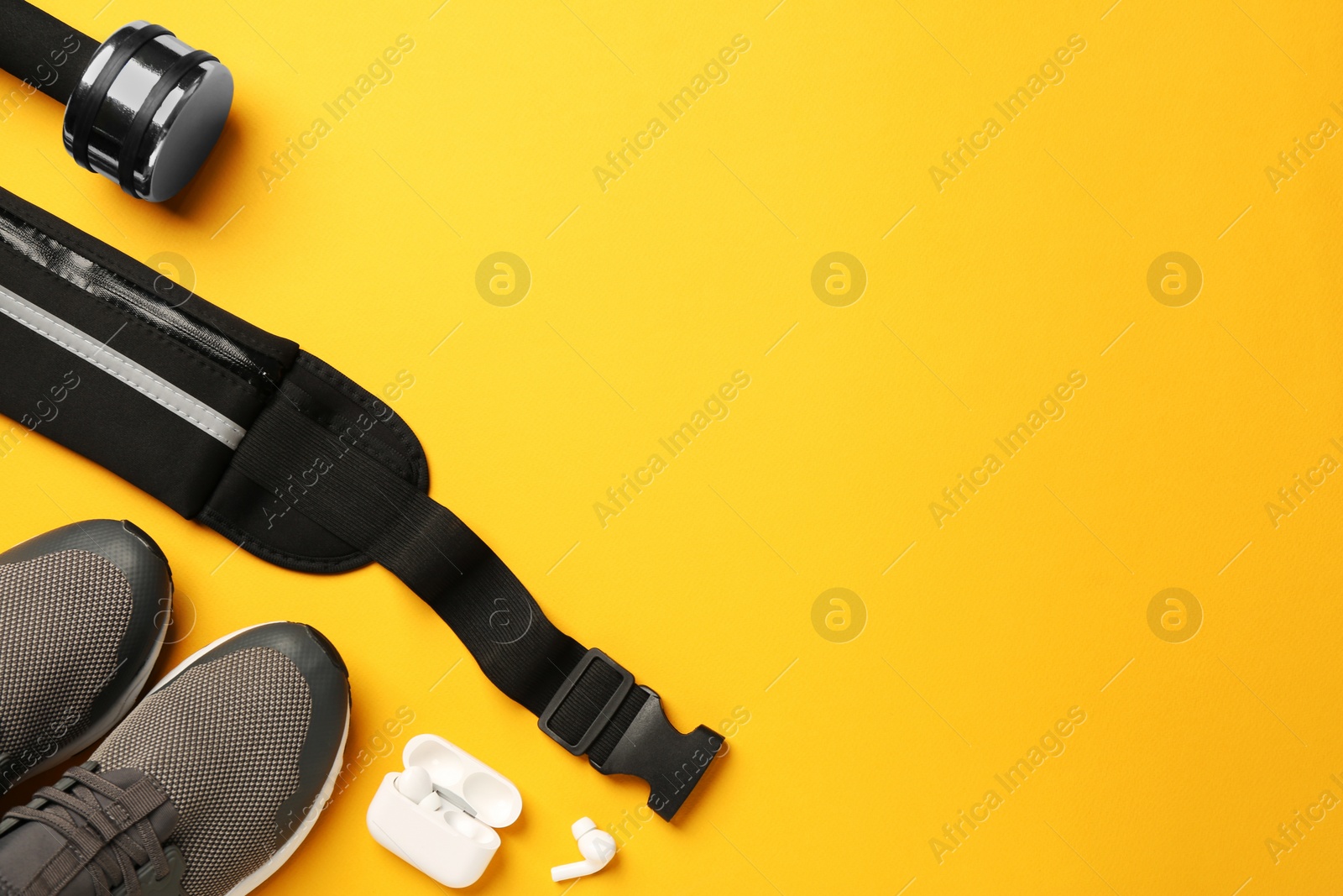 Photo of Flat lay composition with stylish black waist bag on yellow background, space for text