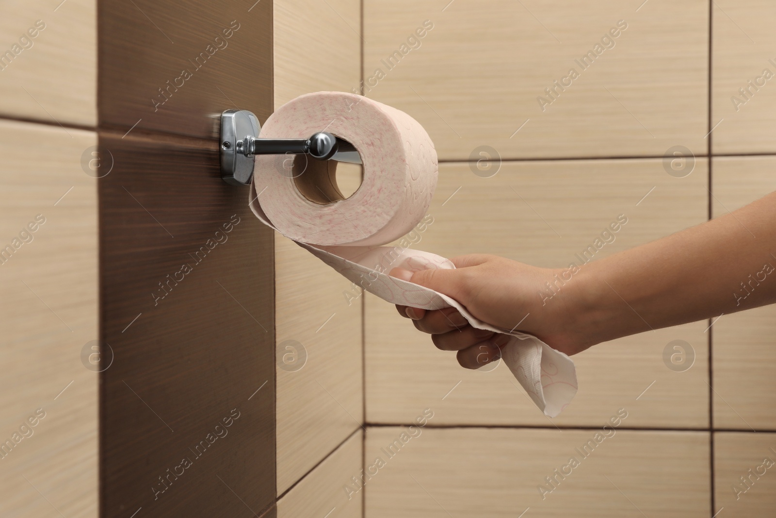 Photo of Woman pulling toilet paper from holder in bathroom