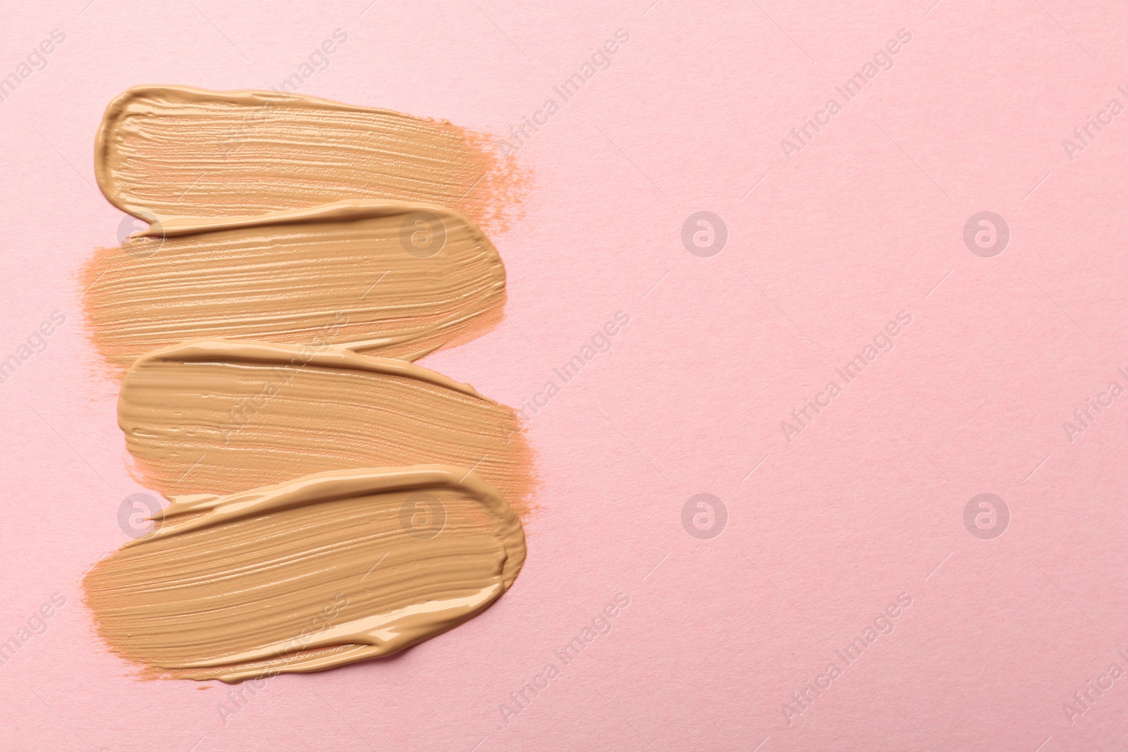 Photo of Sample of liquid skin foundation on pink background, top view. Space for text