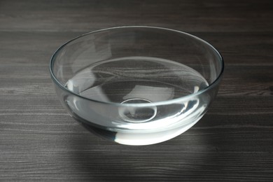 Glass bowl with water on dark wooden table