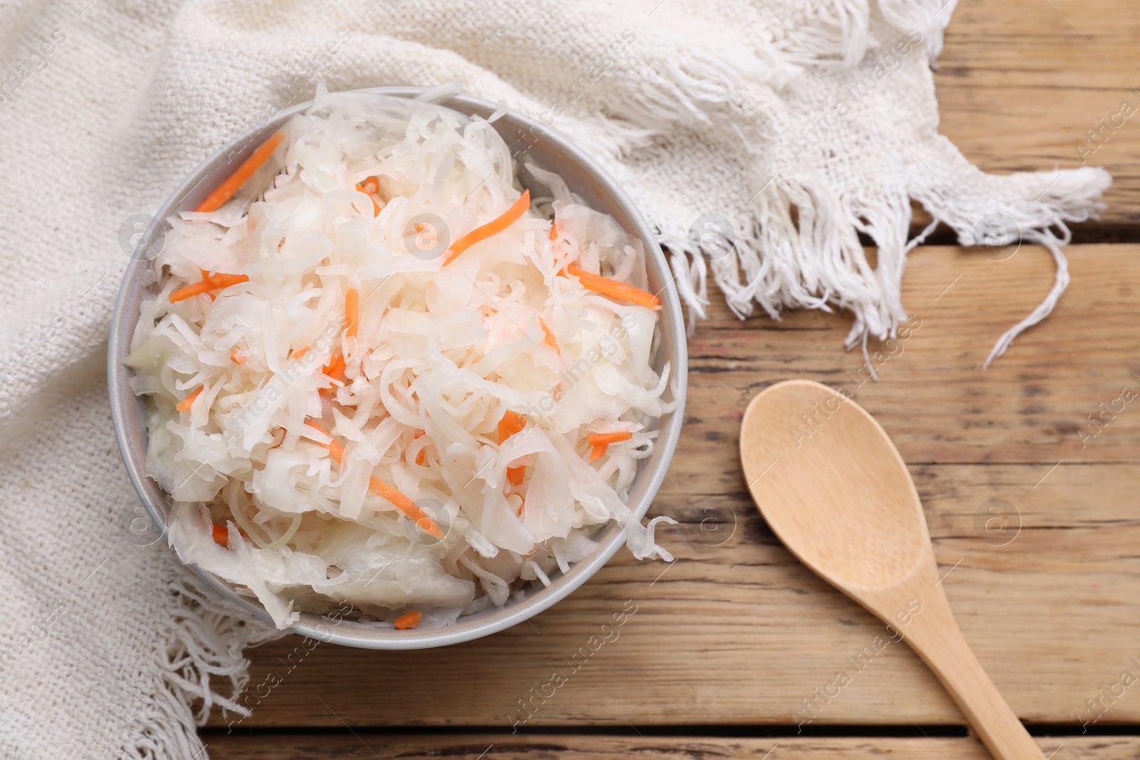 Photo of Bowl of tasty sauerkraut on wooden table, flat lay