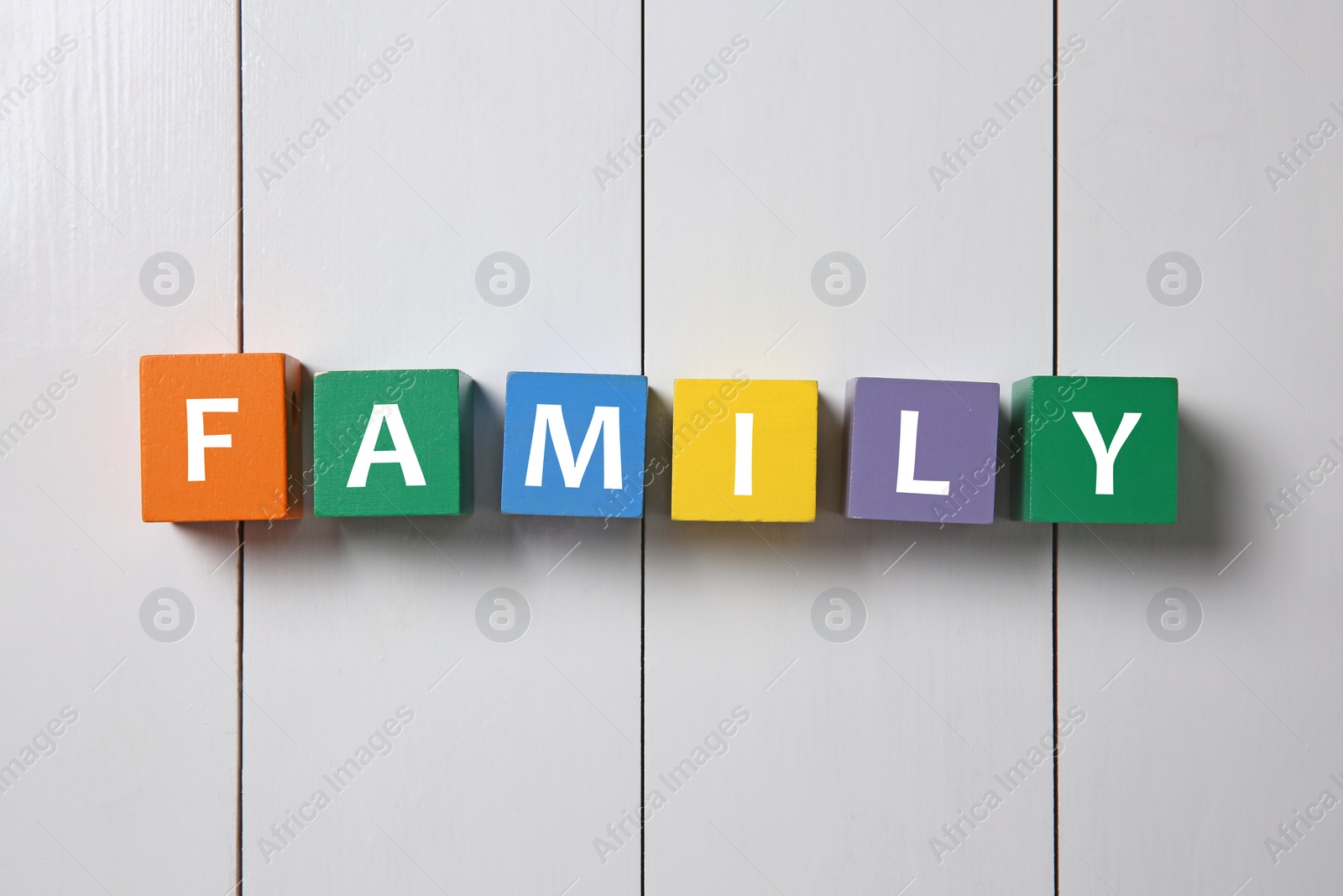 Photo of Colorful cubes with word Family on white wooden background, flat lay