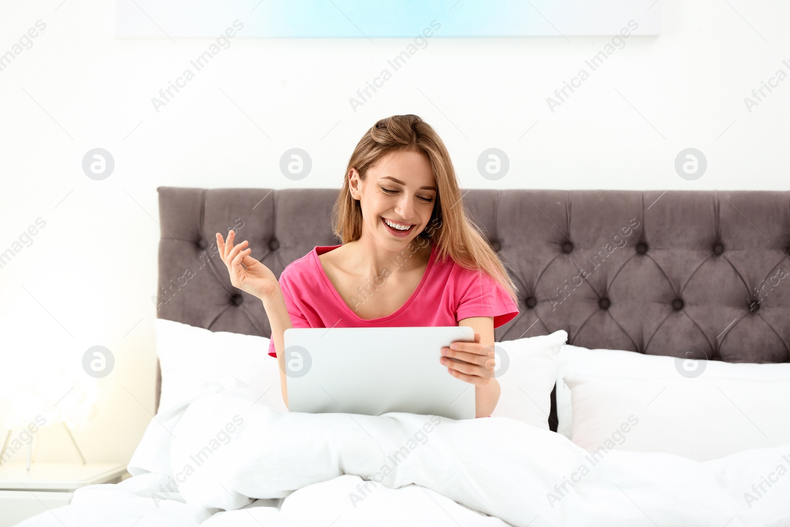 Photo of Young woman using modern laptop in bedroom