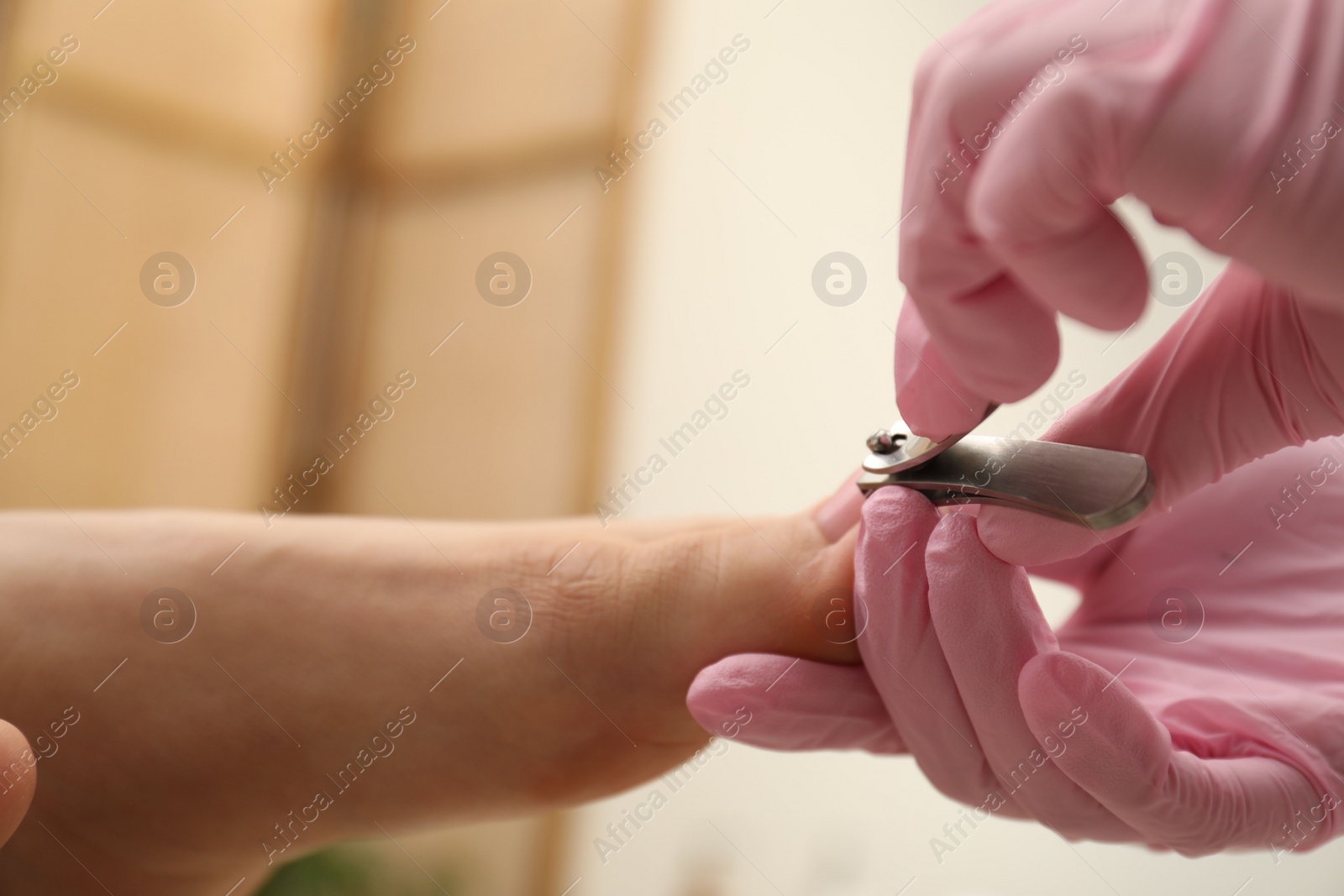 Photo of Professional pedicurist cutting client`s toenails with clipper in beauty salon, closeup