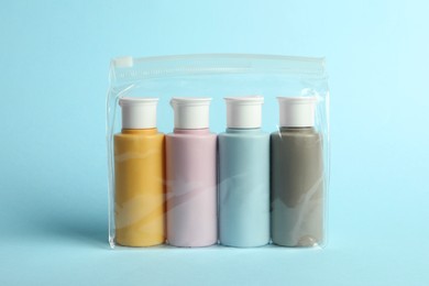 Cosmetic travel kit in plastic bag on light blue background