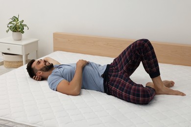 Happy man on bed with comfortable mattress at home