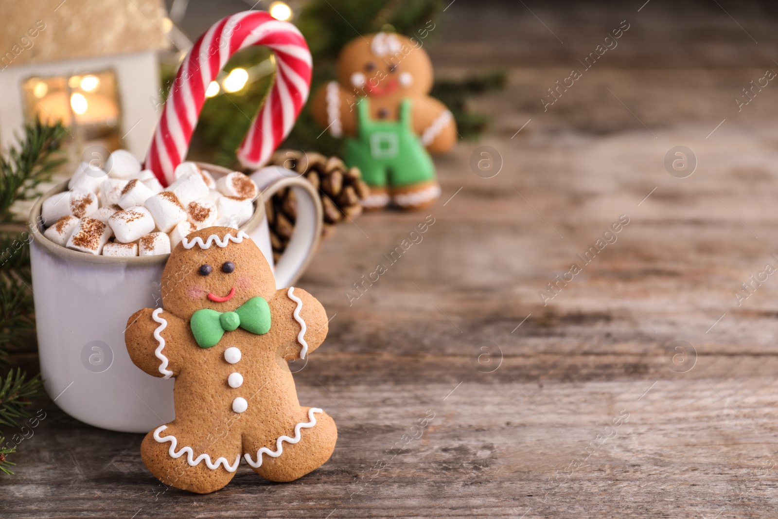 Photo of Gingerbread man and hot drink on wooden table, space for text