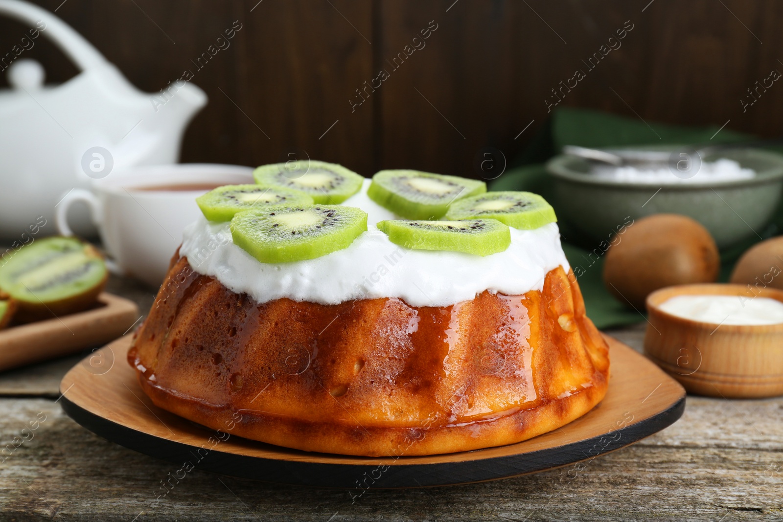 Photo of Homemade yogurt cake with kiwi and cream on wooden table