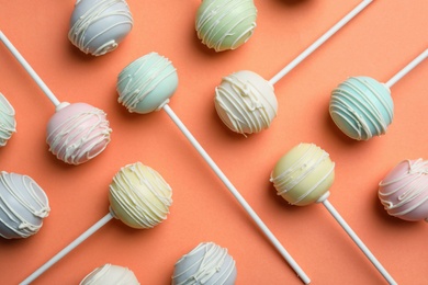 Photo of Sweet cake pops on orange background, flat lay