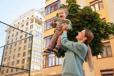 Happy nanny with cute little boy having fun outdoors, space for text