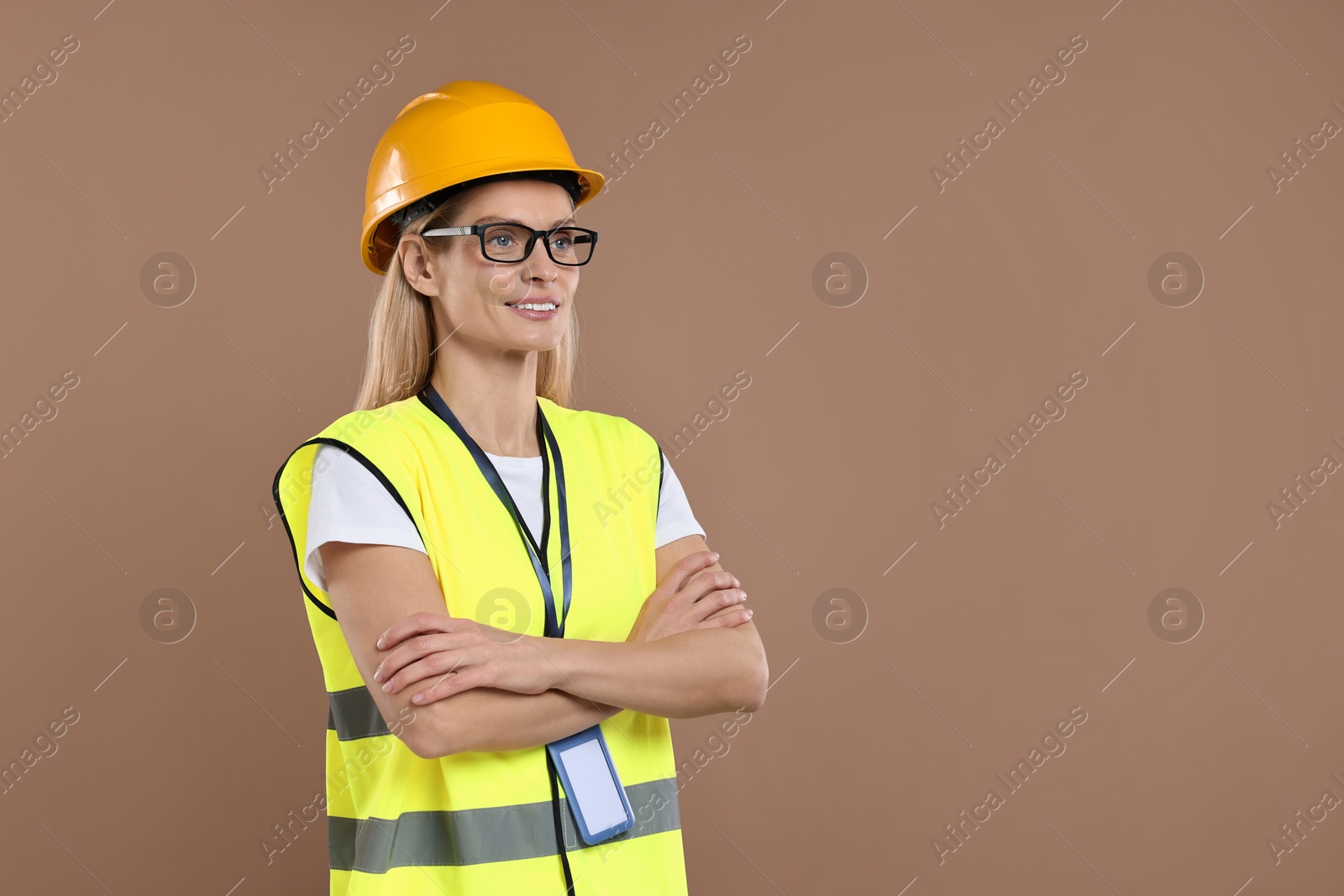 Photo of Engineer with hard hat and badge on brown background, space for text