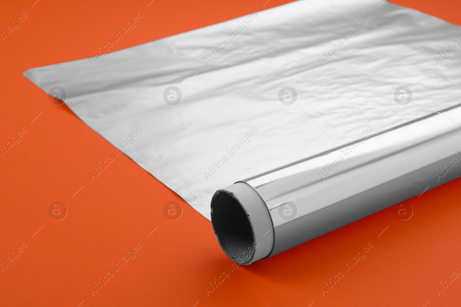 Photo of Roll of aluminum foil on orange background, closeup