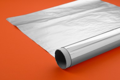 Roll of aluminum foil on orange background, closeup