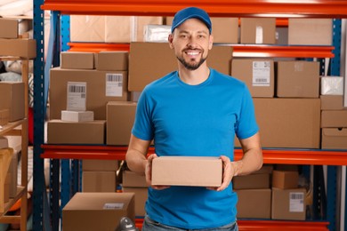 Photo of Post office worker with parcel near rack indoors, space for text