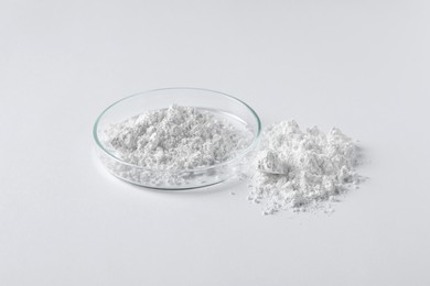 Photo of Petri dish and calcium carbonate powder on white background