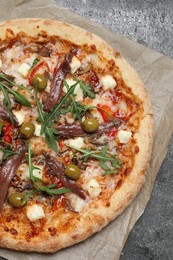 Tasty pizza with anchovies, arugula and olives on grey table, top view