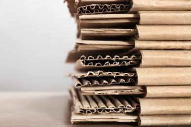 Cardboard pile on table against light background, space for text. Waste recycling concept