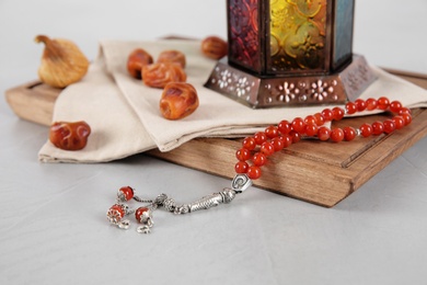 Photo of Muslim lamp, dates and prayer beads on table against white background