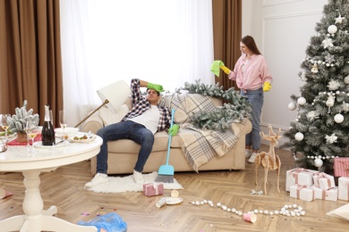 Couple quarrelling in messy room while cleaning after New Year party