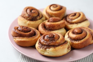 Many tasty cinnamon rolls on white table, closeup