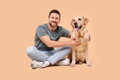 Man hugging with adorable Labrador Retriever dog on beige background. Lovely pet