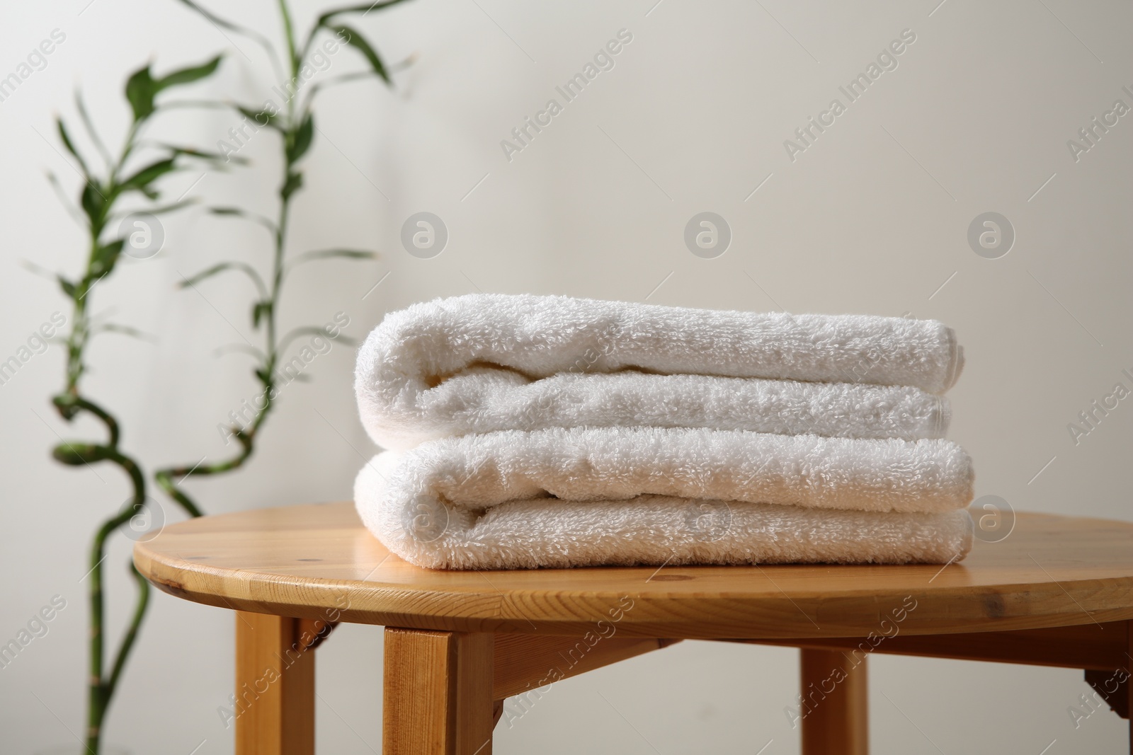 Photo of Folded towels on stool against white wall, closeup